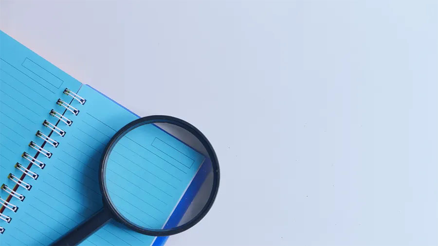 magnifying glass focusing on a spiral bound notebook